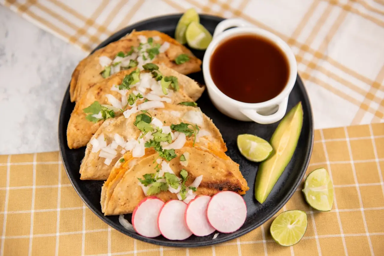 Plate of street tacos with lime and salsa